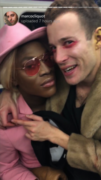 A phone screen displays an Instagram story image, uploaded 7 hours earlier showing a close-up portrait of two people, one wearing a pink suit and tribly, one with zombie make-up. From the short film Pompeii.